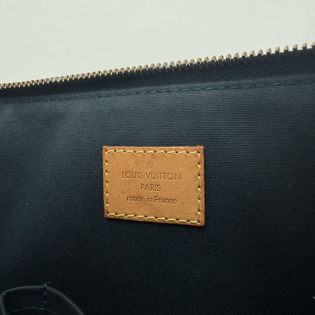 Louis Vuitton bag with a brown leather label on a light gray background