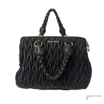 Black quilted MIU MIU  handbag with braided handle on a white background