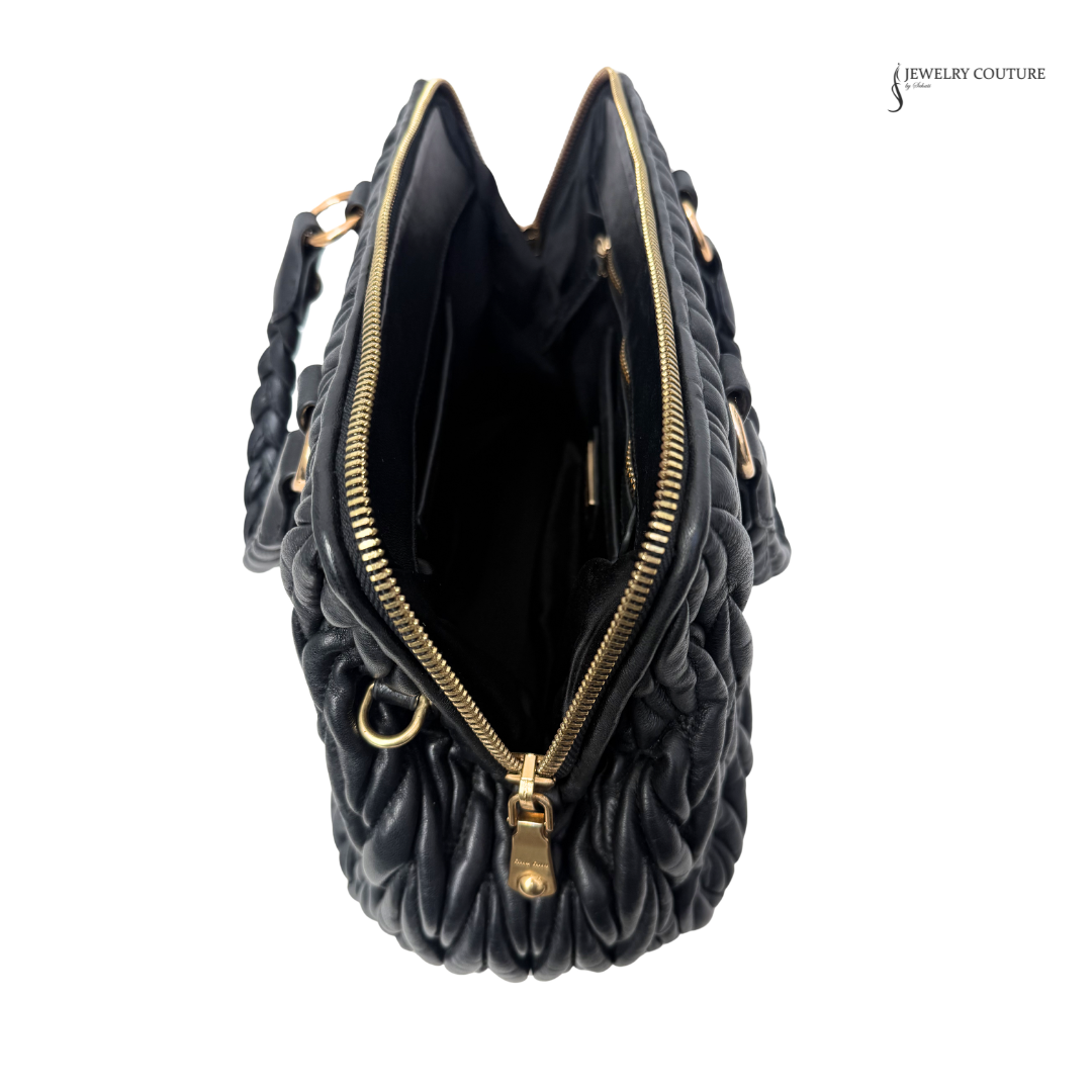 Black quilted handbag with gold zipper on a white background