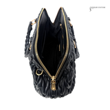 Black quilted handbag with gold zipper on a white background