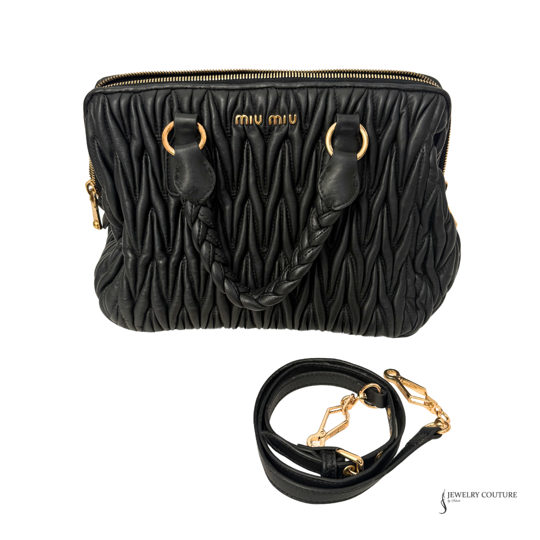 Black textured handbag with gold accents and matching strap on a white background