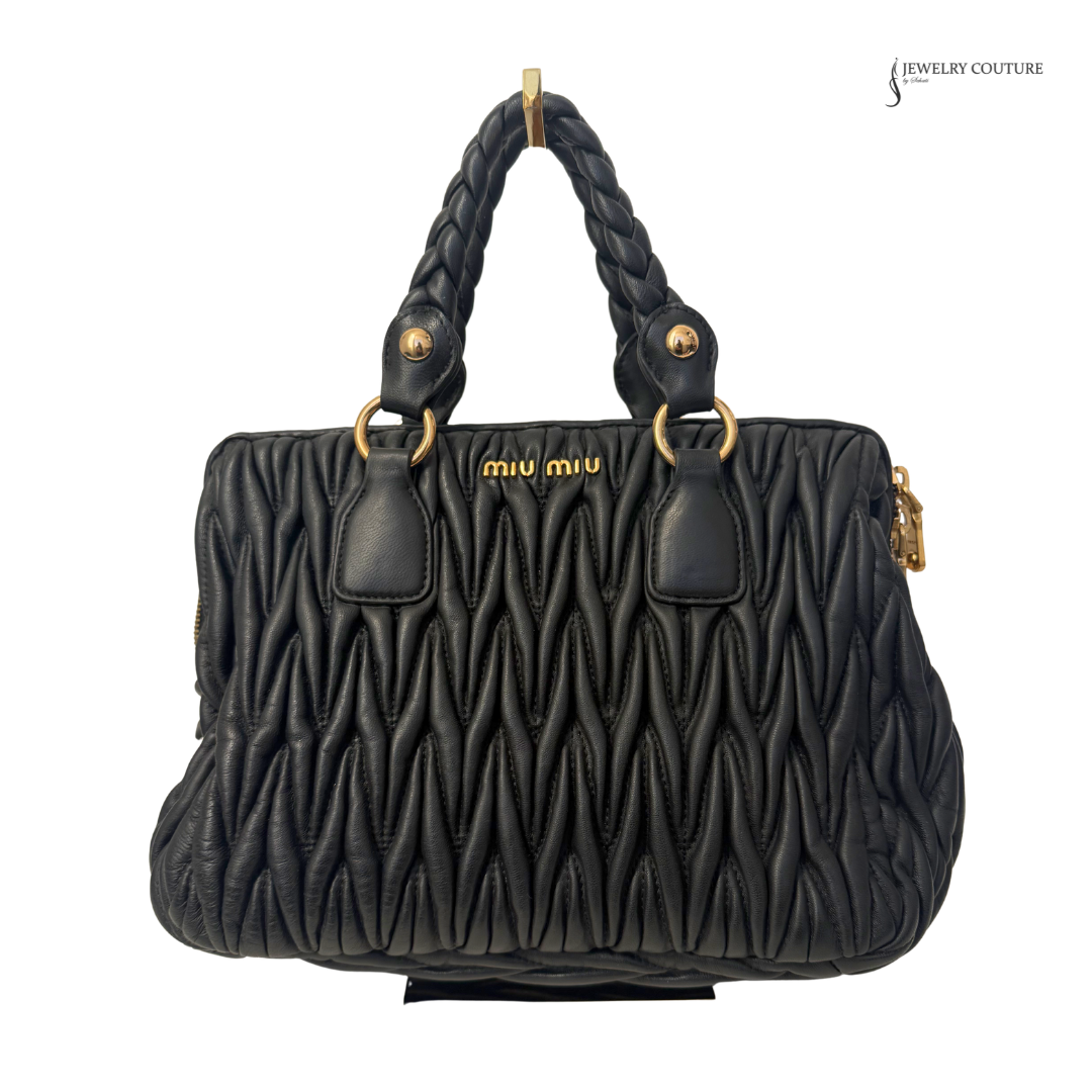 Black quilted handbag with braided handle on a white background