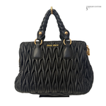 Black quilted handbag with braided handle on a white background