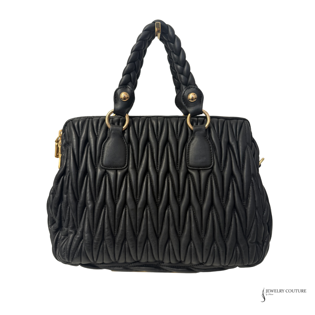 Black quilted handbag with braided handle on a white background