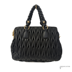 Black quilted handbag with braided handle on a white background