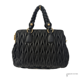 Black quilted handbag with braided handle on a white background