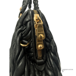 Black textured handbag with gold hardware on a white background