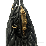 Black textured handbag with gold hardware on a white background