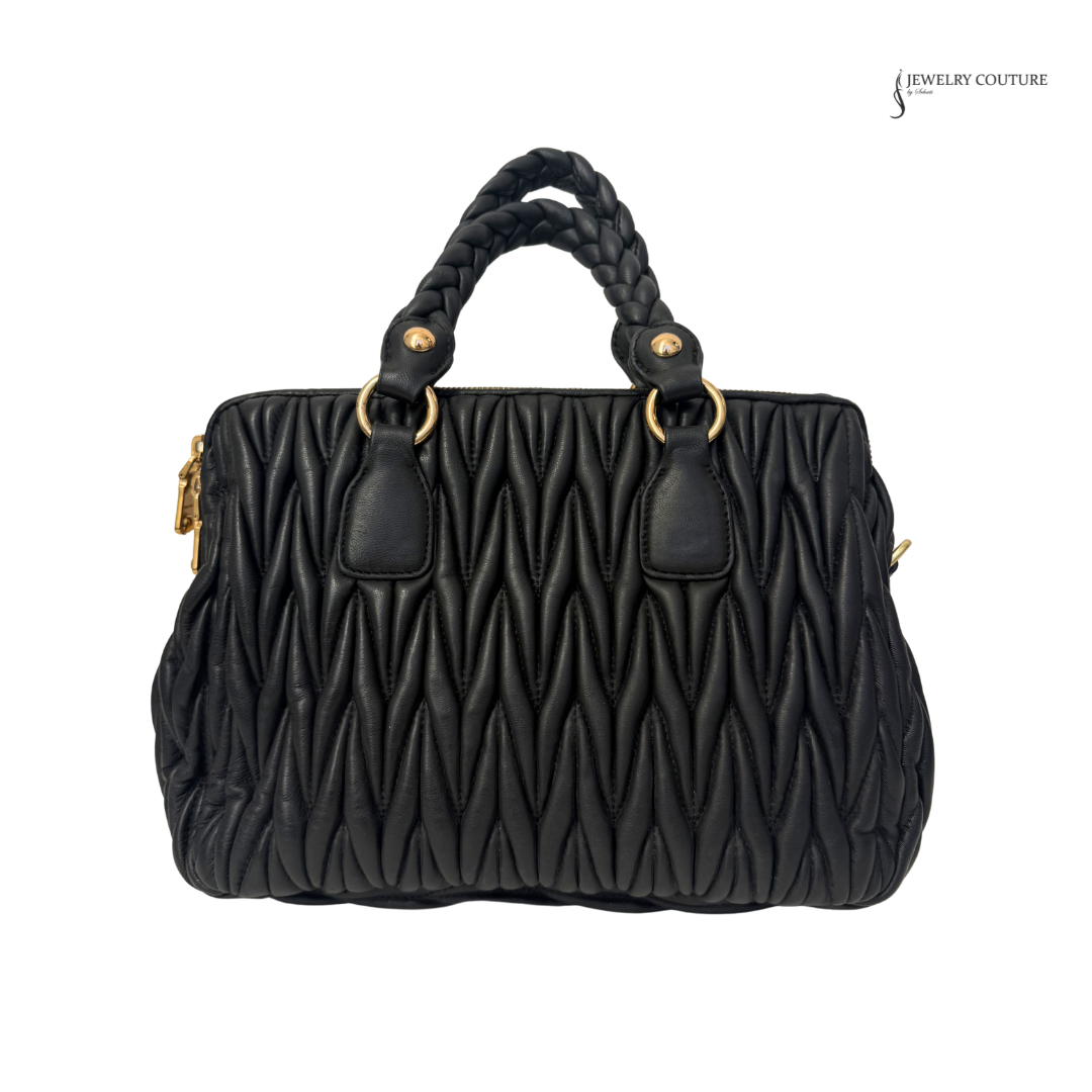 Black quilted handbag with braided handle on a white background
