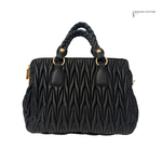 Black quilted handbag with braided handle on a white background