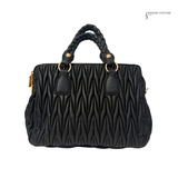Black quilted handbag with braided handle on a white background