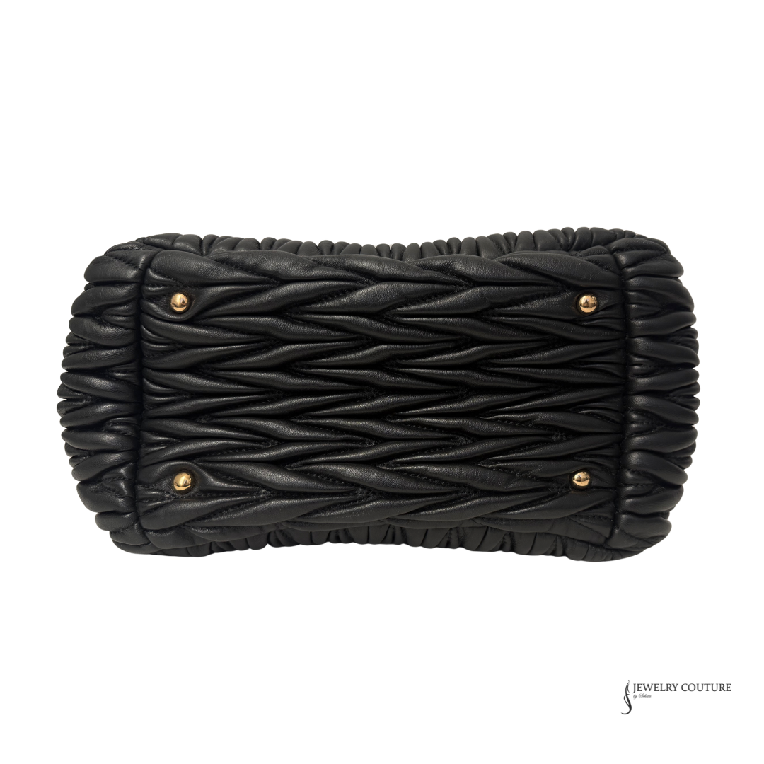Black woven clutch bag with gold accents on a white background