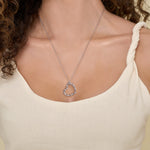 Silver heart-shaped necklace on a person wearing a beige top