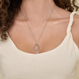 Silver heart-shaped necklace on a person wearing a beige top