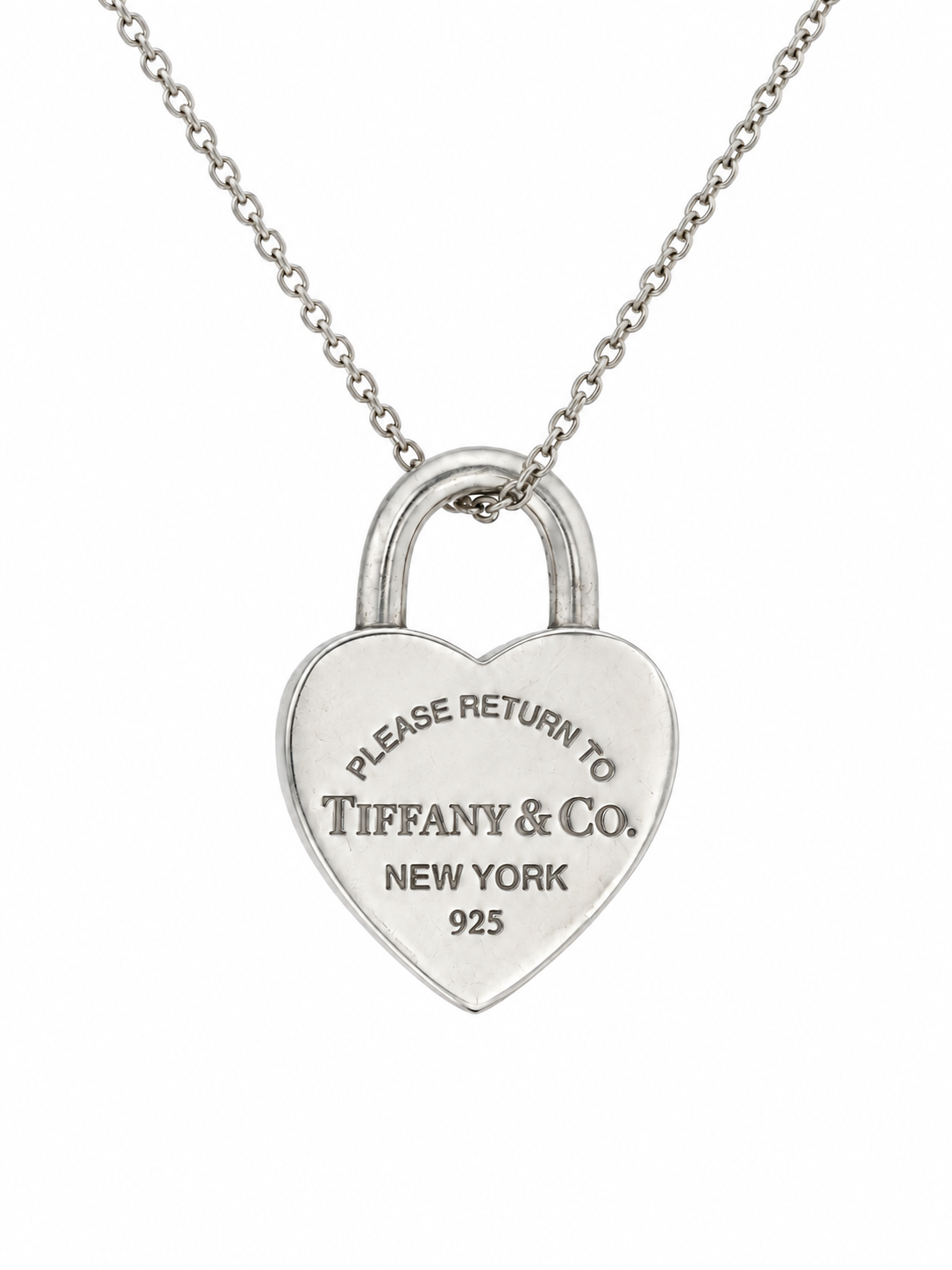 A silver heart-shaped padlock pendant necklace engraved with 'PLEASE RETURN TO TIFFANY & Co. NEW YORK 925', suspended from a delicate silver chain against a plain white background.