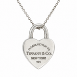 A silver heart-shaped padlock pendant necklace engraved with 'PLEASE RETURN TO TIFFANY & Co. NEW YORK 925', suspended from a delicate silver chain against a plain white background.
