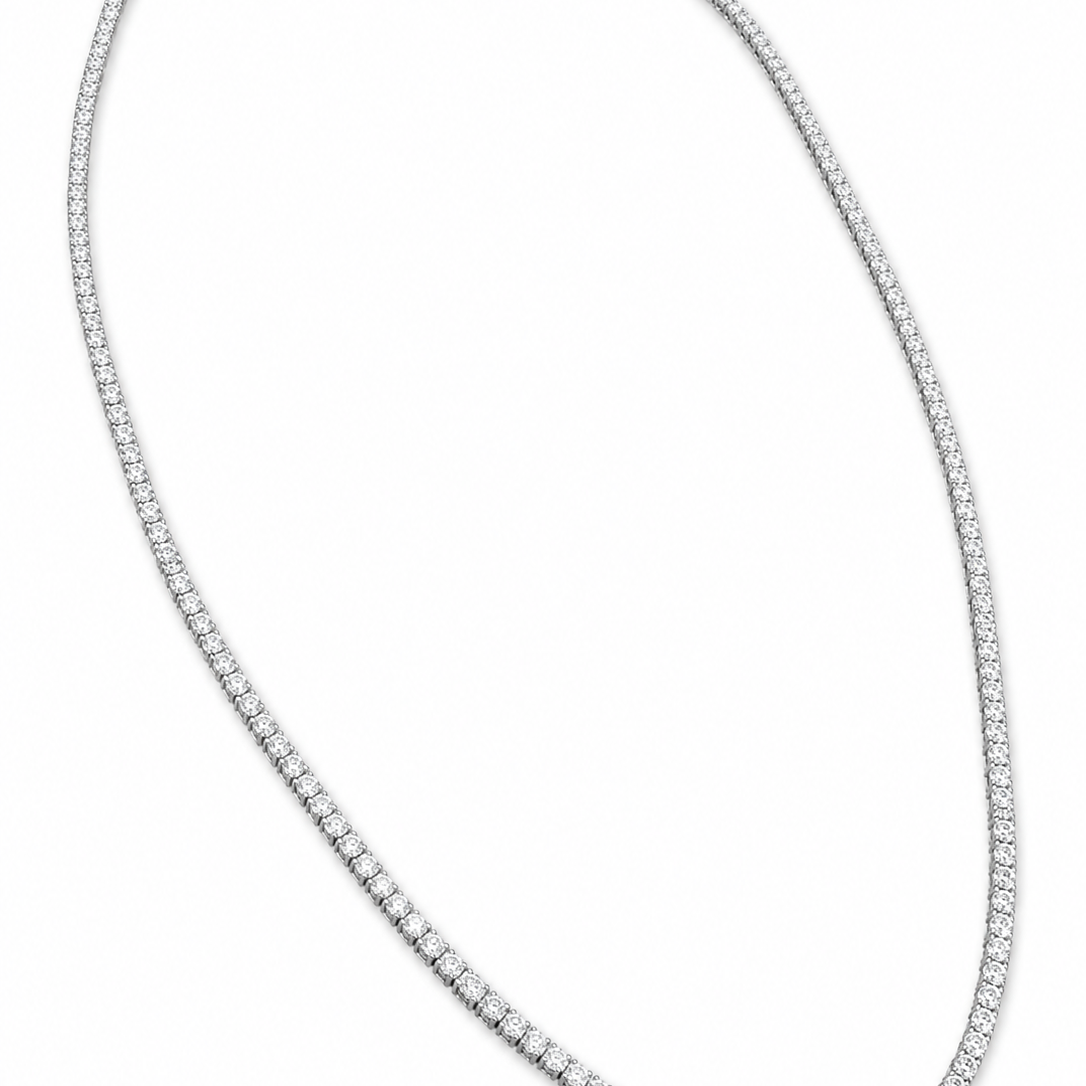A tennis-style diamond necklace in a white-toned metal, arranged in an oval shape on a plain white background.