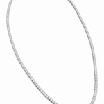 A tennis-style diamond necklace in a white-toned metal, arranged in an oval shape on a plain white background.
