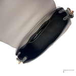 Close-up of a gray handbag with a gold clasp on a white background