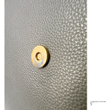 Close-up of a gold button on gray textured fabric with 'Jewelry Couture' branding.