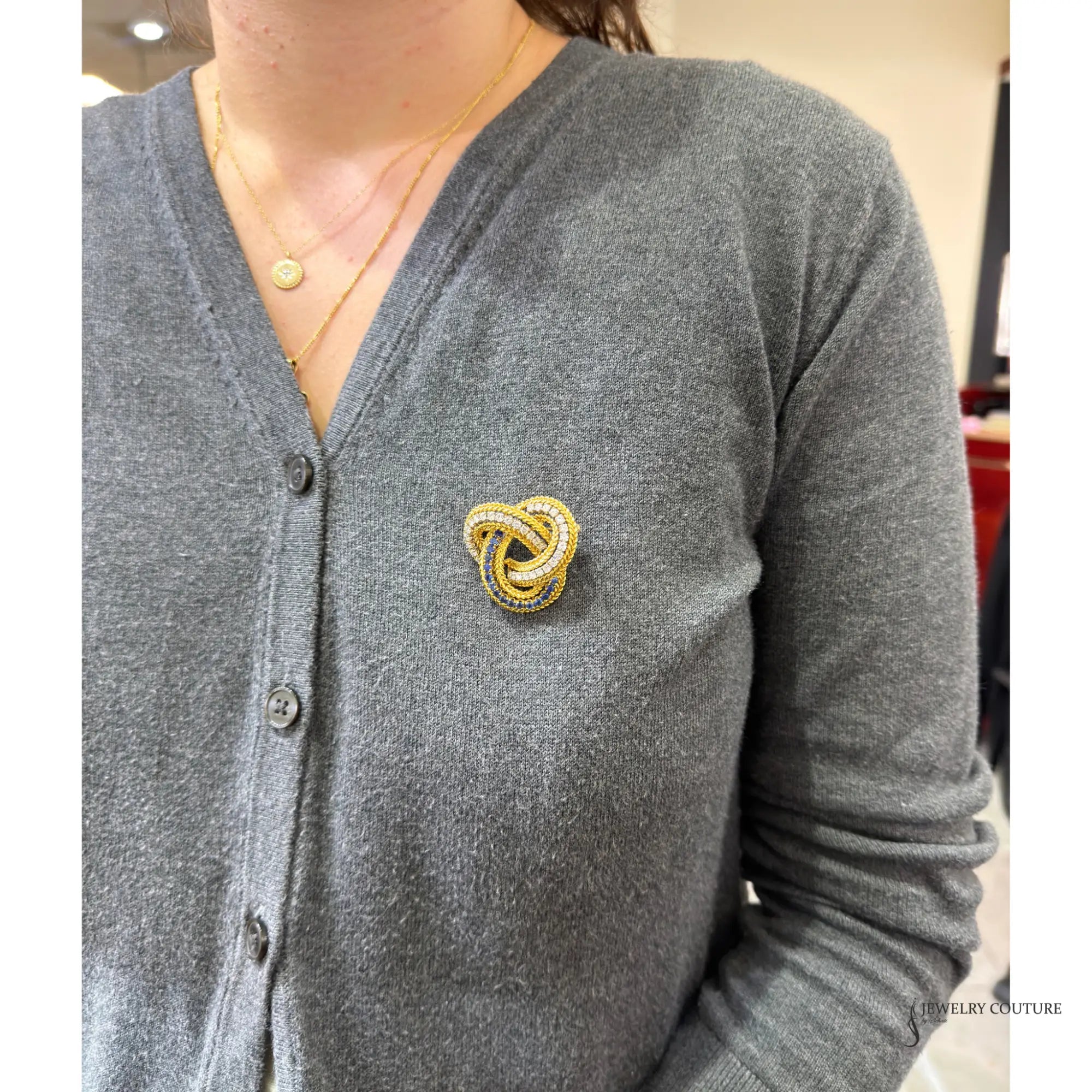 18K gold love knot brooch worn on a cardigan, showing size on the model