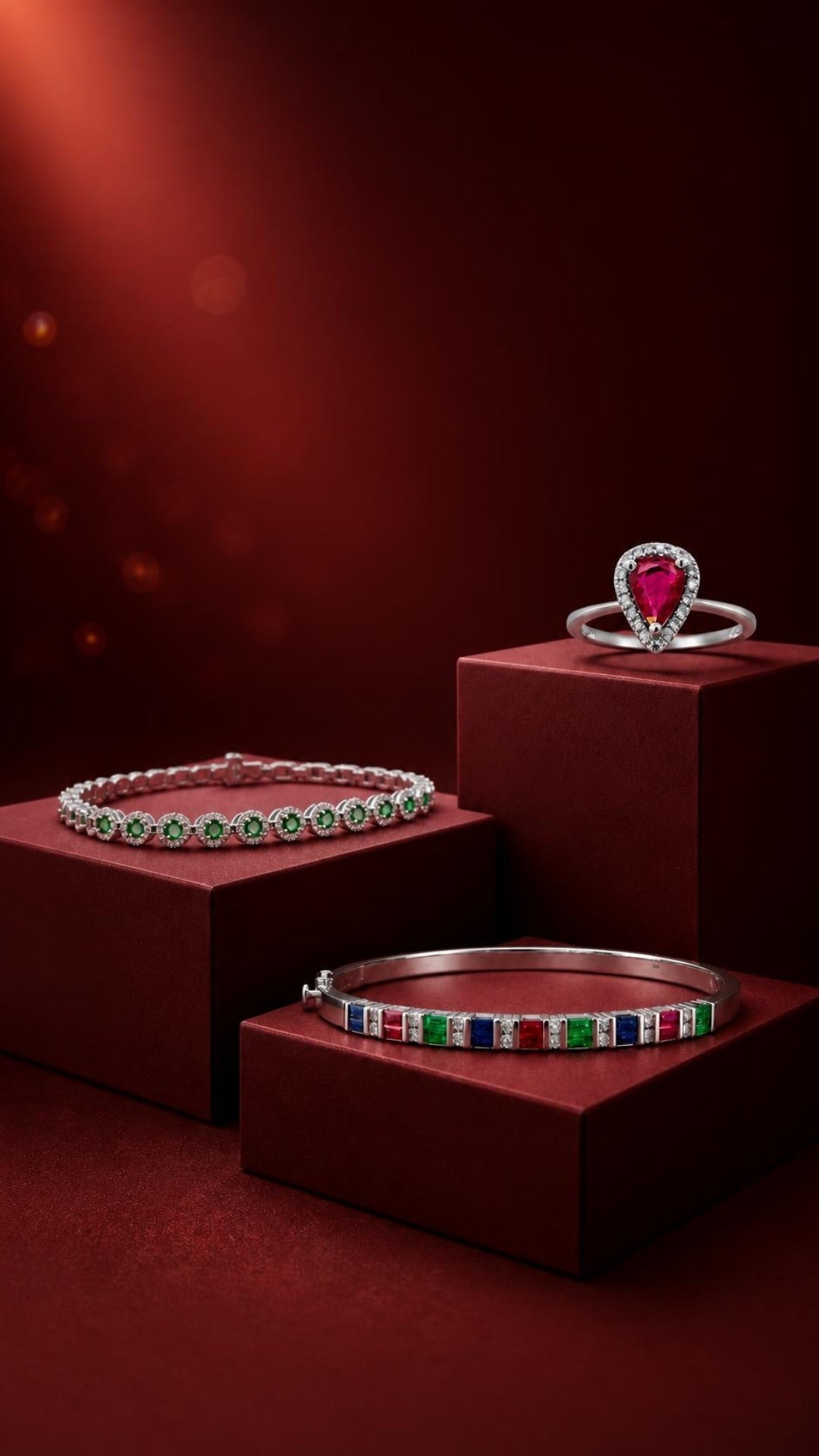 Decoage pear ruby halo ring, tsavorite halo tennis bracelet and multi-gemstone bangle on burgundy pedestals