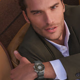Man wearing a watch, sitting in a car interior.