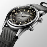 Longines watch with black face and mesh band on a light gray background