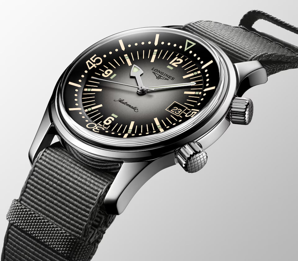 Longines watch with black face and mesh band on a light gray background