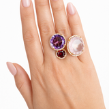 Hand wearing a ring with multicolored gemstones on a white background