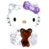 A crystal Hello Kitty figurine with a translucent purple bow and a small translucent brown teddy bear in front, set against a plain white background.