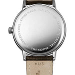 The back view of a Mond Weil wristwatch with a stainless steel case and a beige leather strap, showing engraved details and branding.