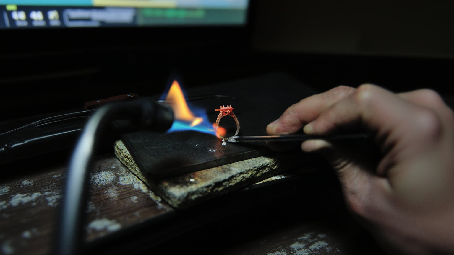 Person holding a ring over a flame on a dark background