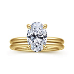 A yellow gold ring with a large oval-cut clear gemstone in a four-prong setting, shown on a plain white background.