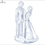 A clear crystal figurine of a groom and bride holding hands, standing on a round base. The Swarovski brand logo is visible in the top-left corner.