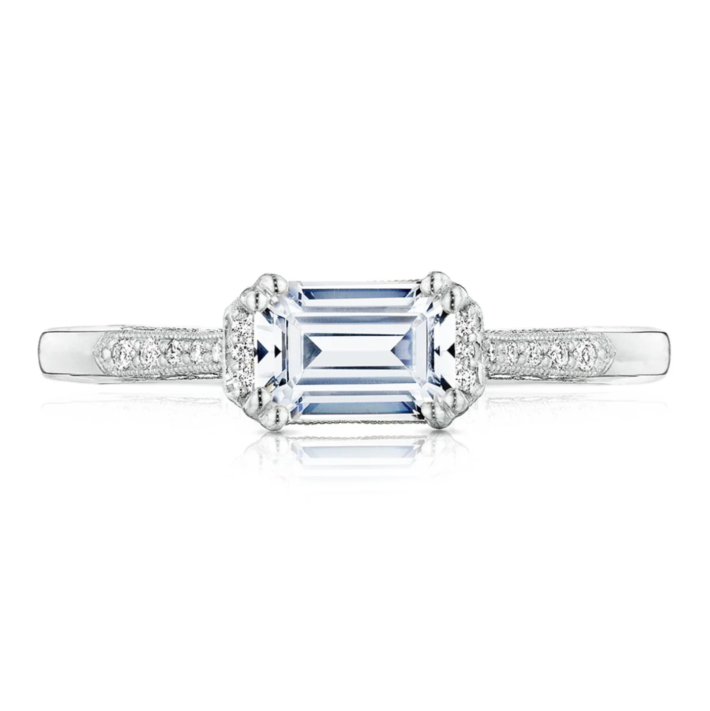 Diamond ring with a central emerald-cut gemstone on a white background