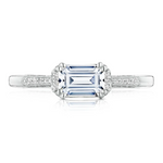 Diamond ring with a central emerald-cut gemstone on a white background