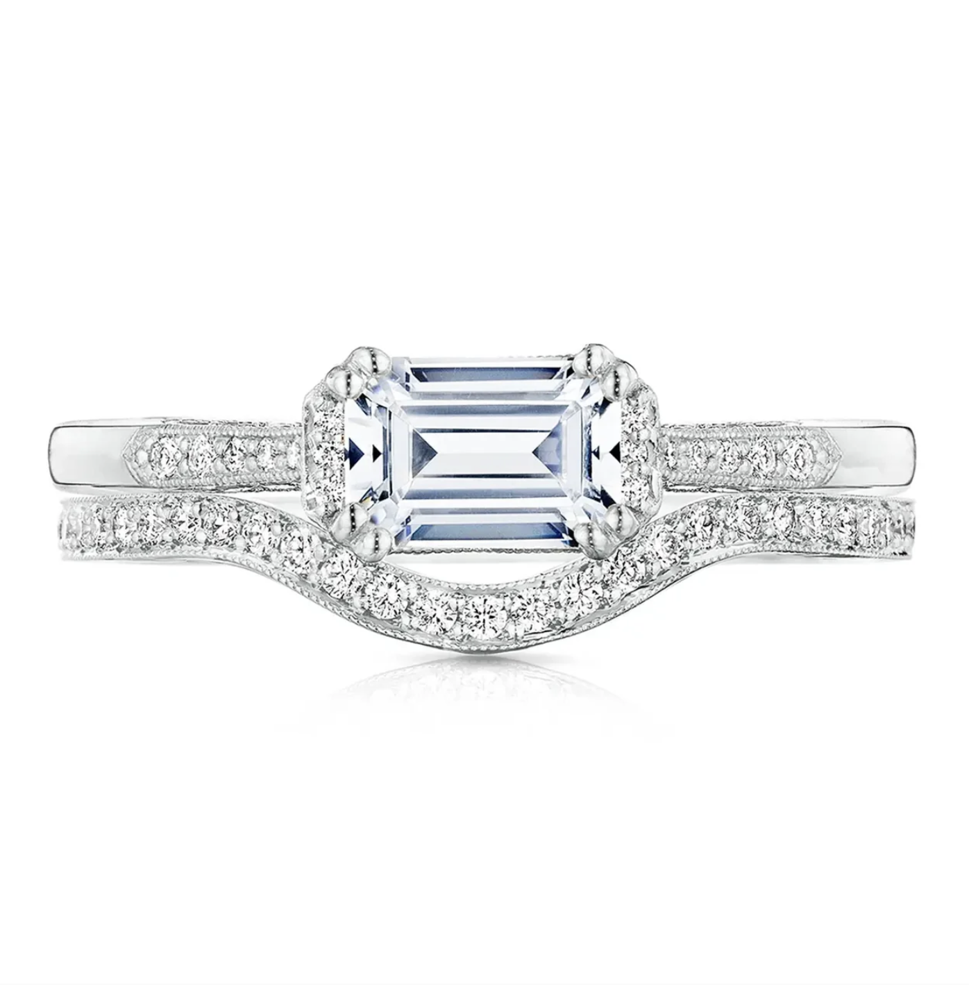Diamond ring with a central emerald-cut gemstone and diamond-studded band on a white background