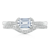 Diamond ring with a central emerald-cut gemstone and diamond-studded band on a white background