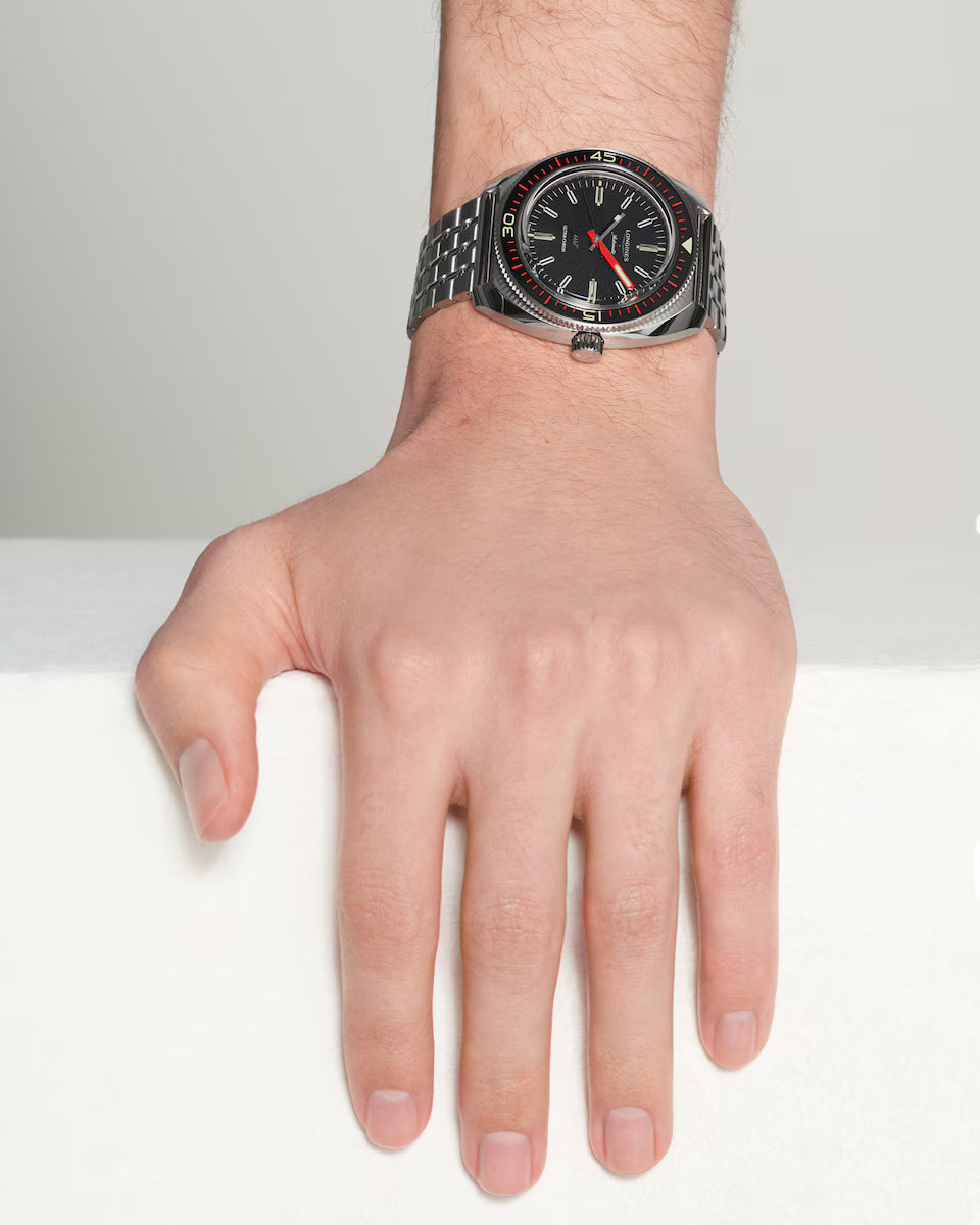 Hand wearing a black wristwatch with a white background
