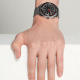 Hand wearing a black wristwatch with a white background