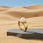 Gold ring with a pearl on a stone platform in a desert setting